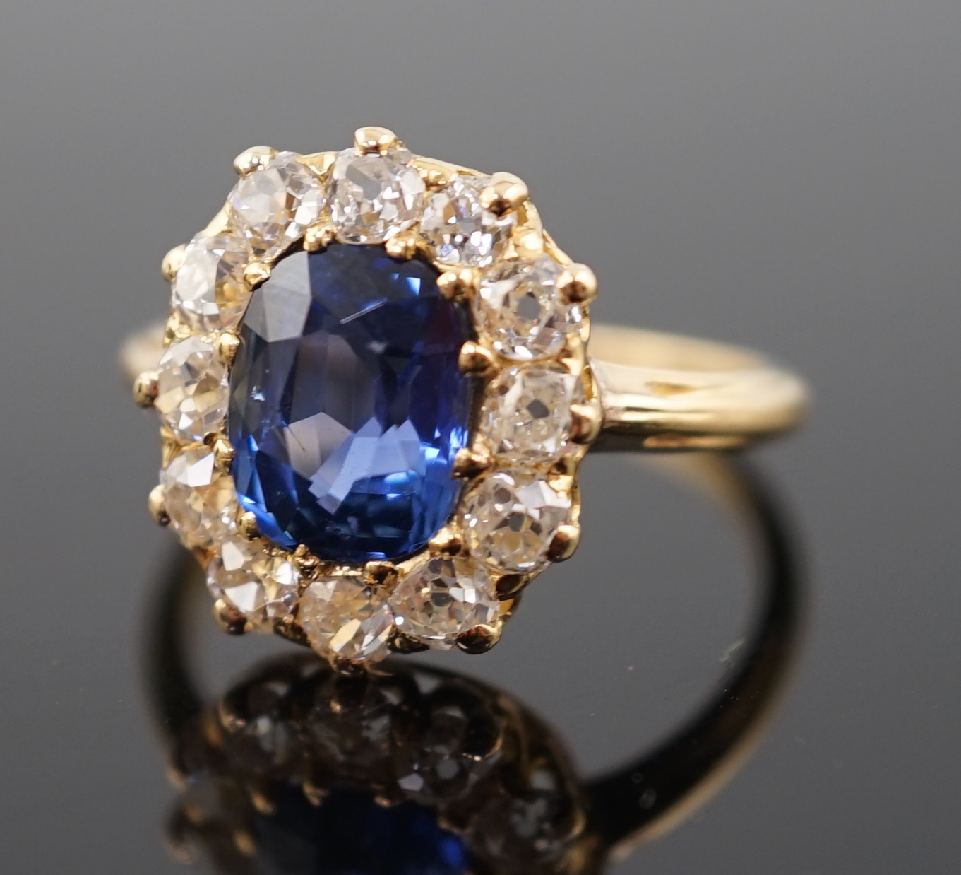 A gold, sapphire and old round cut diamond set oval cluster ring